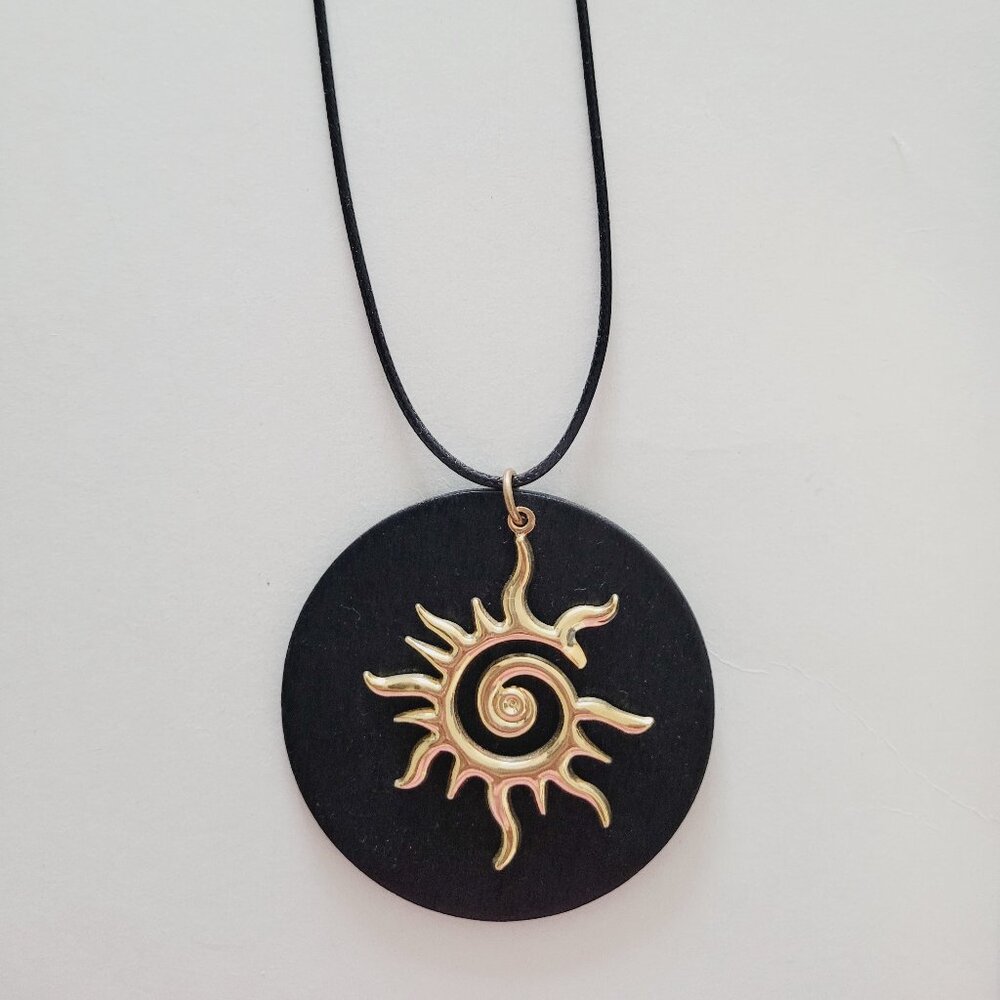 Collar de sol dorado sobre madera negra artesanal